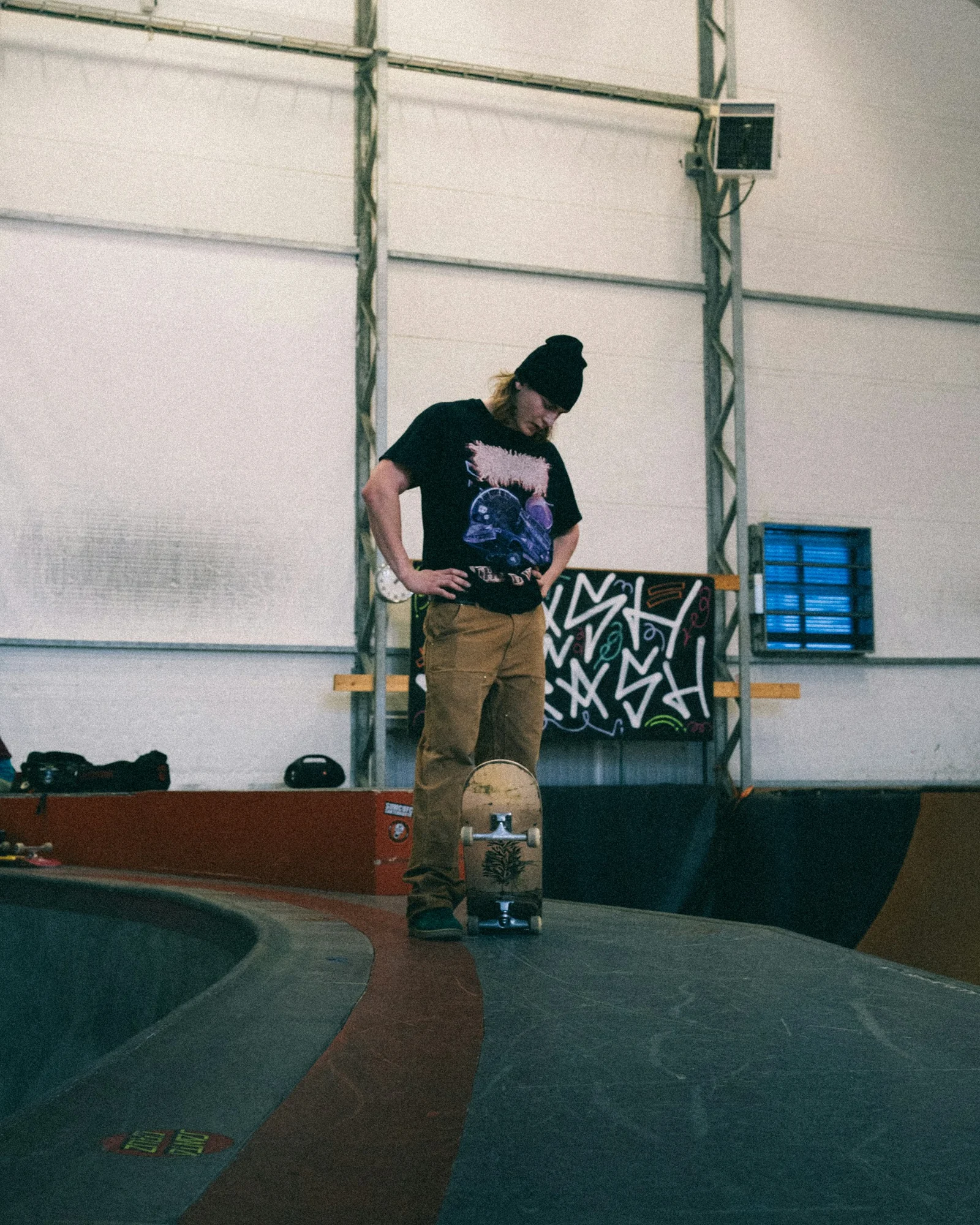 A person stands with a skateboard in a skatepark.;第三方摄影参考